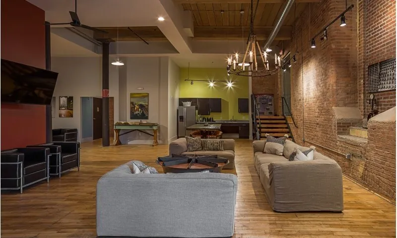 Spinning community room with chandelier, sofas and original brick at Drayton Mills Lofts