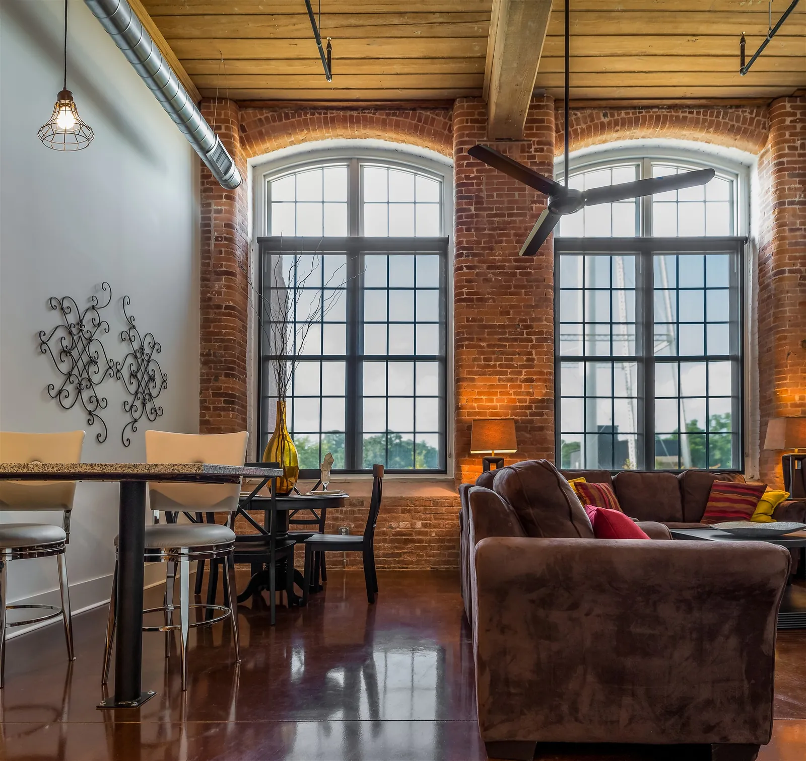 Loft living room with arched mill windows, exposed brick and original hardwood at Drayton Mills Lofts