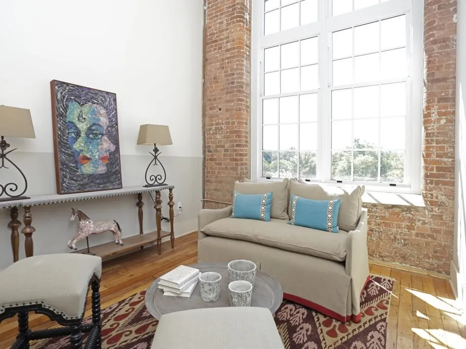 Loft living room with exposed brick wall and tall windows at Drayton Mills Lofts