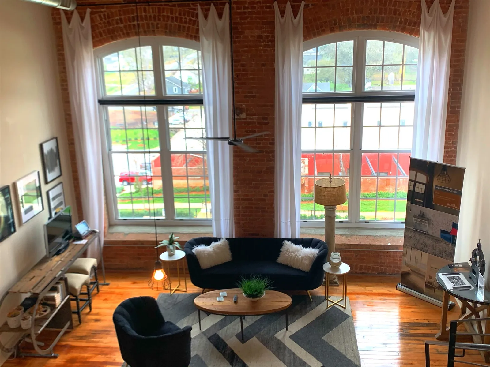 Living area of three bedroom loft S325 at Drayton Mills beneath the mezzanine, with arched mill windows
