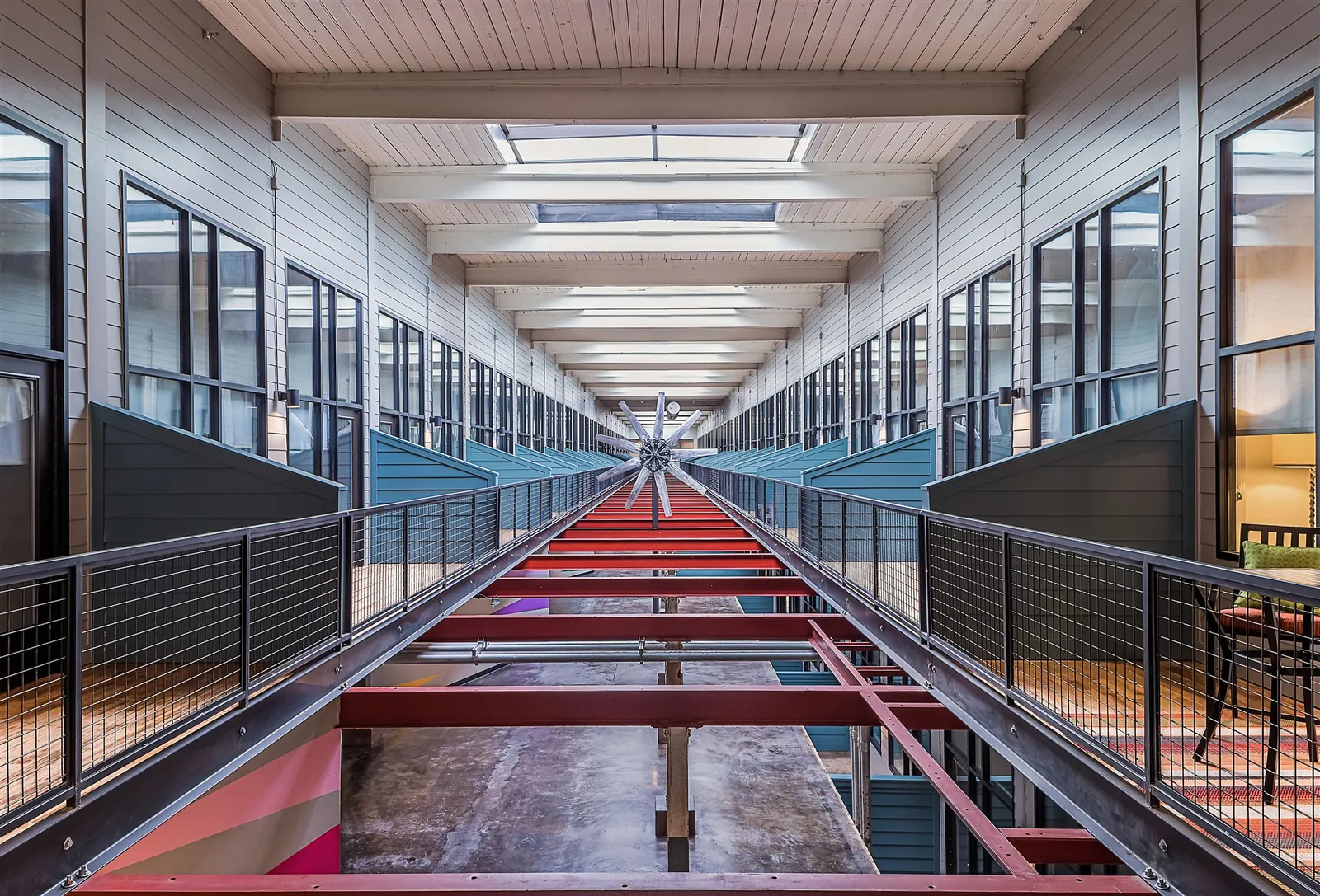 The Weaving building atrium at Drayton Mills Lofts with glass-walled corridors and steel railings